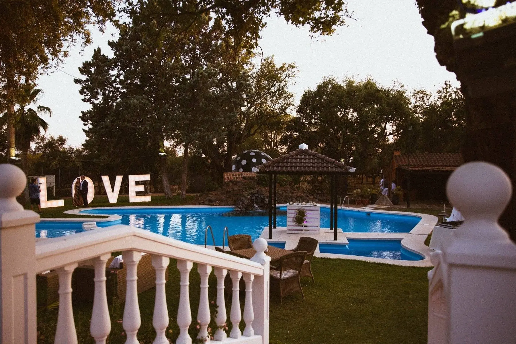 La piscina vista desde una balaustrada blanca, con las letras LOVE y el templete al fondo